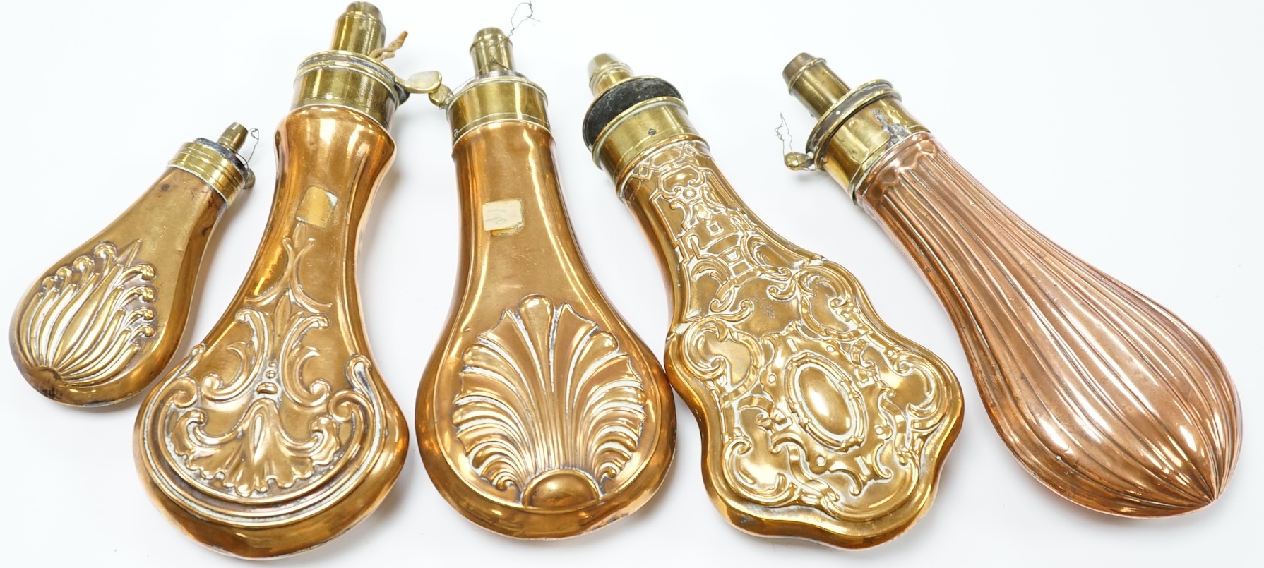 Five 19th century copper and brass powder flasks, all with embossed decoration to the bodies. Condition - fair